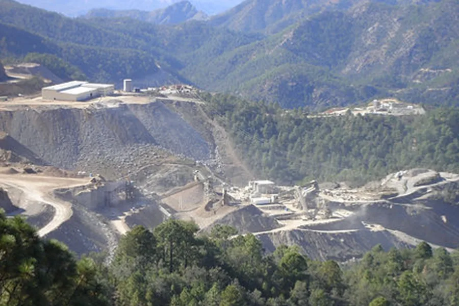 Vista de la operación de Ocampo, con la planta de proceso, los bancos de mina y los patios de mineral entre las montañas boscosas de Chihuahua.
